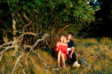 Naklejka na ściany i meble Young beautiful enamored couple walking outdoors in summer at sunset