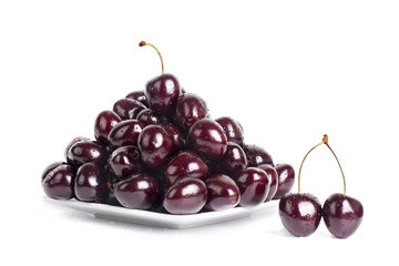 Cherry berries in water drops on a white plate on a white background isolated