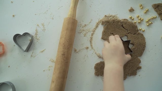 baby's hand cuts a starlet biscuit from a dough
