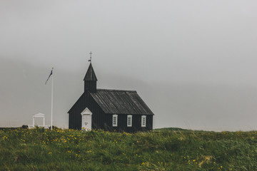 Fototapeta premium dramatic shot of Budir church on green field at Snaefellsnes, Iceland