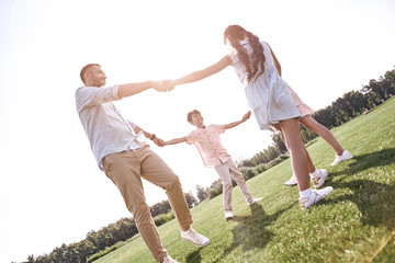 Bonding. Family of four holding hands dancing in circle on a gra