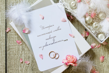 Two Golden Wedding Rings, box of chocolates and a wedding invitation, an inscription that the story of true love never ends. Top view flat lay background.