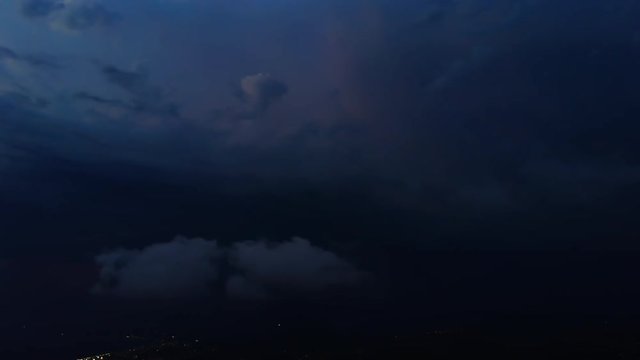 Timelapse of beautiful thunderstorm with picturesque lightning illuminating the sky with orange and yellow colors. Many dramatic lightning flashes on the stormy sky over the night coastal city.