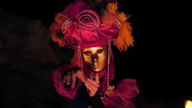 The face of the girl at the masquerade in a Venetian suit hides a mysterious mask. Dance with fire in the night. Concept idea for dance