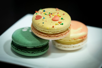 Obraz na płótnie Canvas Homemade assorted macarons beautifully decorated with colorful hearts, green tea and yellow and gold color