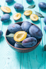 Fresh plums in bowl on wooden table