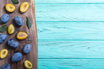 Fresh plums in bowl on wooden table