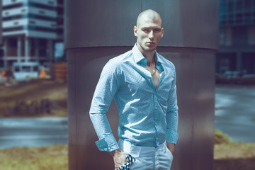 Young and bald sexy guy in a shirt posing in Moscow city