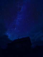 Star tracks upon village house. Starry night sky in cloudy weather. Kenozersky National Park, Arkhangelsk region, Russia.