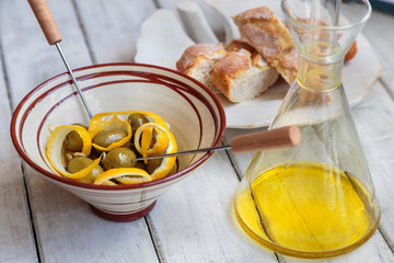 olives with lemon zest, garlic and olive oil in a clay dish.