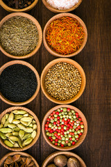 Spices on a wooden background in bowls, place of copying, seasoning, saffron, cumin, black sesame, cardamom, nutmeg, pink salt, star anise, coriander