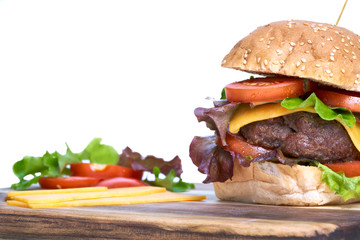 A cheese burger with lettuce, tomatoes and sesame bread bun isolated on a white background.