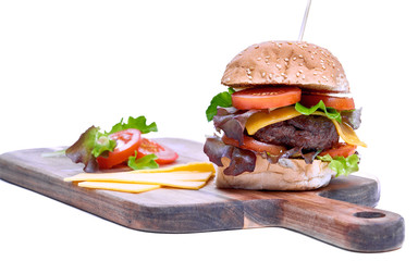 A cheese burger with lettuce, tomatoes and sesame bread bun isolated on a white background.