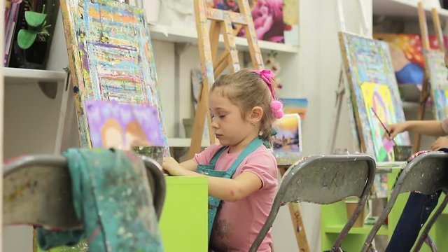 Little girl in art school paints a picture