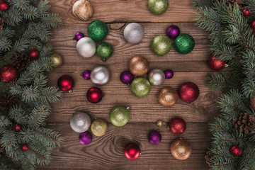 top view of shiny colorful baubles and christmas tree branches on wooden background