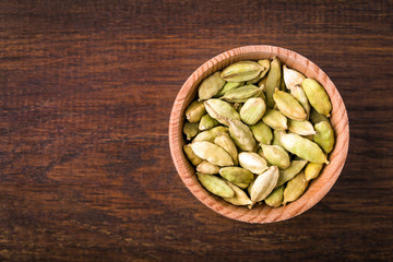 Cardamom, pods in a cup on a wooden background, Indian spice