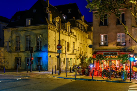 Fototapeta Cozy street with tables of cafe in Paris at night, France