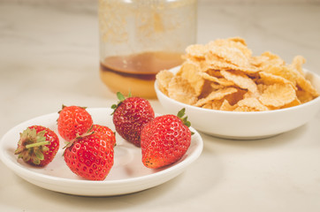 breakfast with strawberry, flakes and honey/healthy concept: breakfast with strawberry, flakes and honey on a white marble background, selective focus