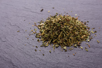 dried tarragon and essential oil on a dark stone background