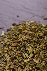 dried tarragon and essential oil on a dark stone background