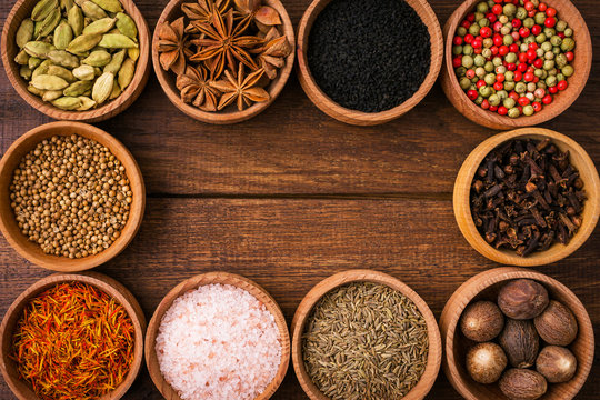 Spices on a wooden background in bowls, frame, place of copying, seasoning, saffron, cumin, black sesame, cardamom, nutmeg, pink salt, star anise, coriander © yakovlevadaria