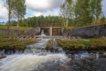Fototapeta na wymiar The reservoir, the water flows through a stream of wooden logs.