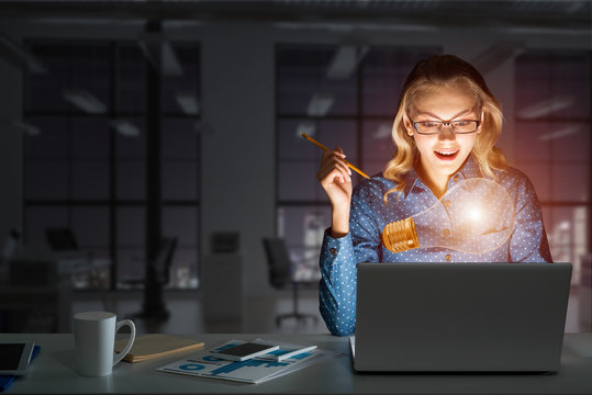 Attractive blonde wearing glasses in dark office using laptop. Mixed media