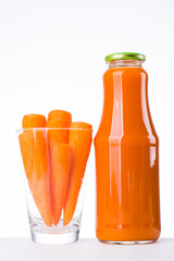 a glass with carrots and carrot juice in a bottle