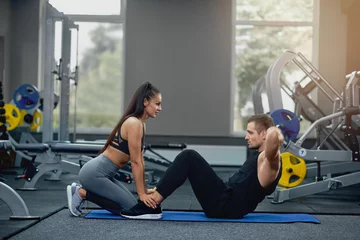  Man doing abdominal crunches press exercise with female personal trainer. © serhiibobyk