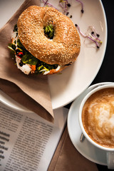 Morning meal, bagel burger with fresh salad and coffee. Top view shot. Gourmet conception.