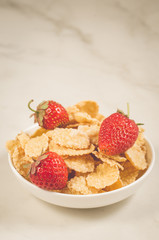 healthy concept with strawberry and flakes/strawberry and flakes in white bowls on a marble background. Selective focus