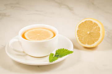 herbal tea with a lemon and mint/herbal tea with a lemon and mint on a white marble background. Selective focus