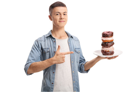 Teenage boy holding a pile of donuts on a plate and pointing with finger