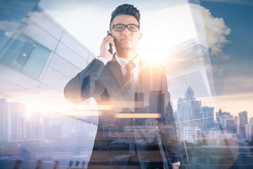 The double exposure image of the businessman using a smartphone during sunrise overlay with cityscape image. The concept of modern life, business, city life and internet of things.