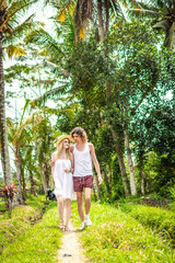 Naklejka premium Young honeymoon couple walking among rice fields. Beautiful trip of newleds to Bali island, Indonesia. Nature, summer, green, bright.