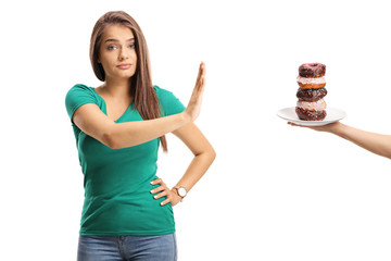 Young woman refusing a plate of donuts