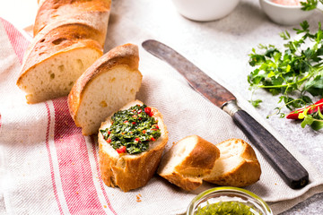  Argentinian green Chimichurri with ingredients.Raw homemade with baguette.Salsa or sauce made of parsley, garlic, oregano, hot pepper, olive oil, vinegar.Food Concept.