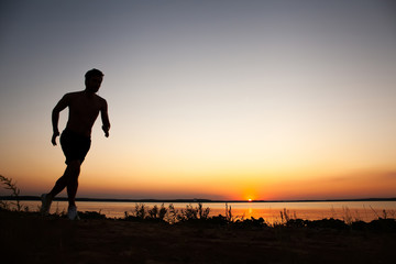 Fototapeta na wymiar Running man silhouette in sunset time. Sport and active life concept.