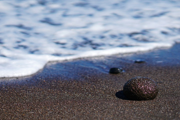Rock on the sand on the Paradisos beach of Santorini
