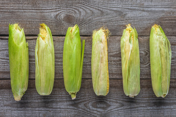elevated view of autumnal corn cobs on grey wooden tabletop