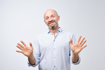 Friendly guy in white casual shirt gesturing Fine, it is enough. Mature european man raising hands...