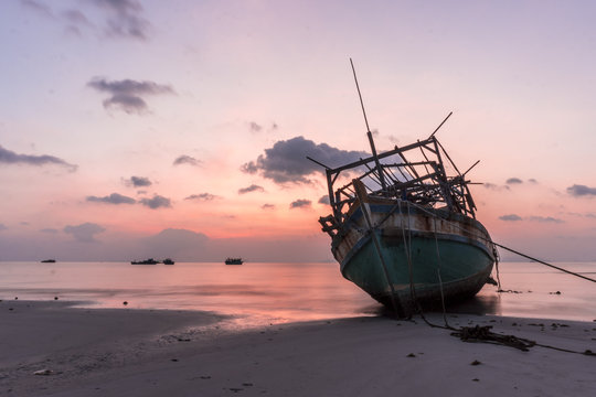 The old wooden ruined fishing boats set aground on the beach at Sunset time