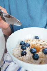 Healthy breakfast oatmeal with banana, blueberries, honey and pine nuts