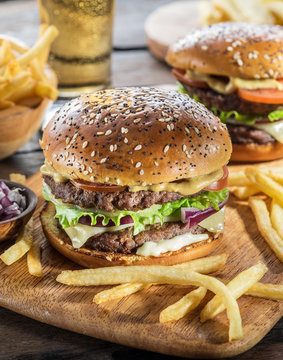 Hamburgers and French fries on the wooden tray.