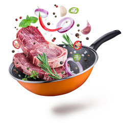 Flying meat steaks and spices over a frying pan. File contains clipping path.