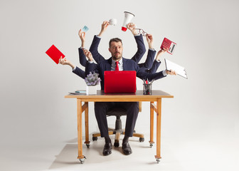 businessman with many hands in elegant suit working and holding office tools. Isolated over white...
