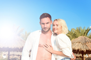  Beautiful young couple having vacation on a sunny beach walking while holding hands, hugging, and taking selfies.  Happy handsome man and blonde woman in white shirts enjoying their trip to hawaii.