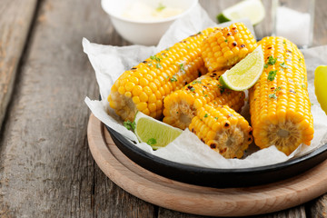 Homemade golden sweet corn cob with butter and salt on wooden background.