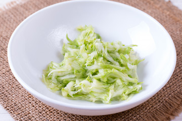 Bowl of grated zucchini on a white background