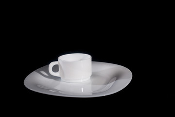 White plate with a mug on a black background